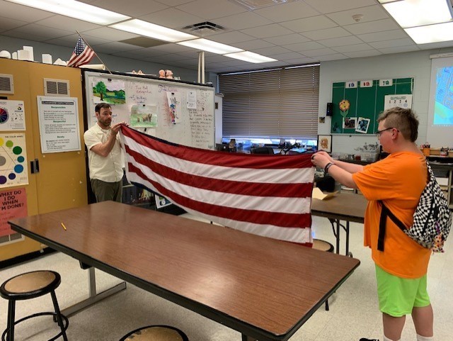 flag raiser / one teacher and one student properly folding the american flag in a classroom setting